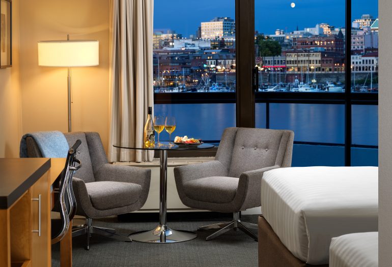 laurel wing guest room view at night with 2 chairs and a table between them with wine and charcuterie on it