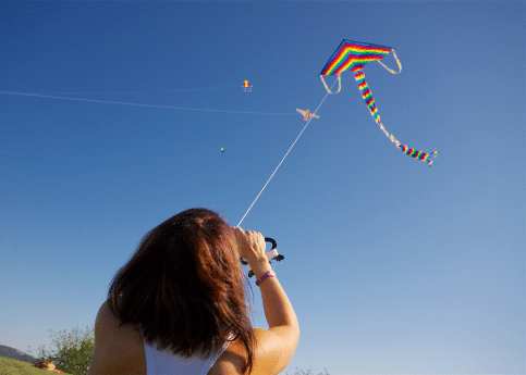 the back of a woman flying a kite in blue sky