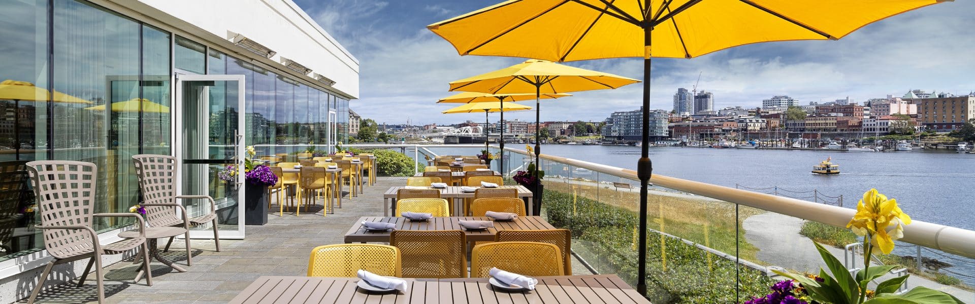 patio in the summer with umbrellas open at Key to the City partner Aura Waterfront Restaurant + Patio