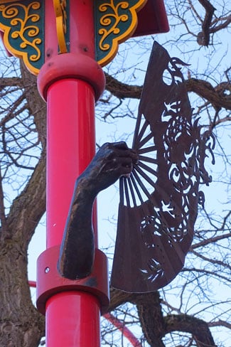 sculpture on a post of a hand holding a fan, photo credit: Penny Pitcher