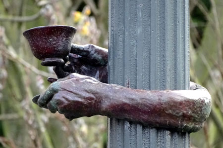 sculpture on a lamp post of hands raising a tea cup, photo credit: Penny Pitcher