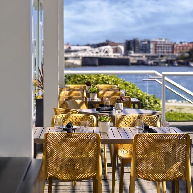 close up of a patio set on a sunny day with no people at Aura Waterfront Restaurant + Patio