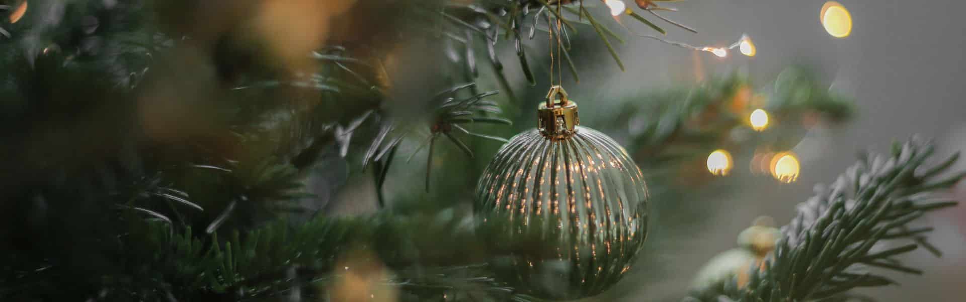 close up of ornament dangling from Christmas tree with lights blurred
