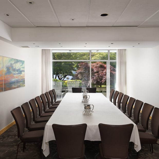 Stone Room, a meeting room at Inn at Laurel Point set as a boardroom, with patio and harbour views in the background