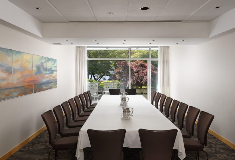 Stone Room, a meeting room at Inn at Laurel Point set as a boardroom, with patio and harbour views in the background